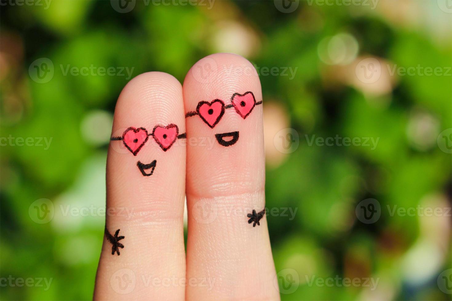 Finger art of a Happy couple. A man and a woman hug in pink glasses in shape of hearts. The concept of love at first sight. photo