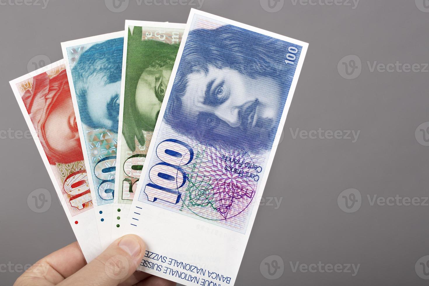 Old Swiss franc in the hand on a gray background photo