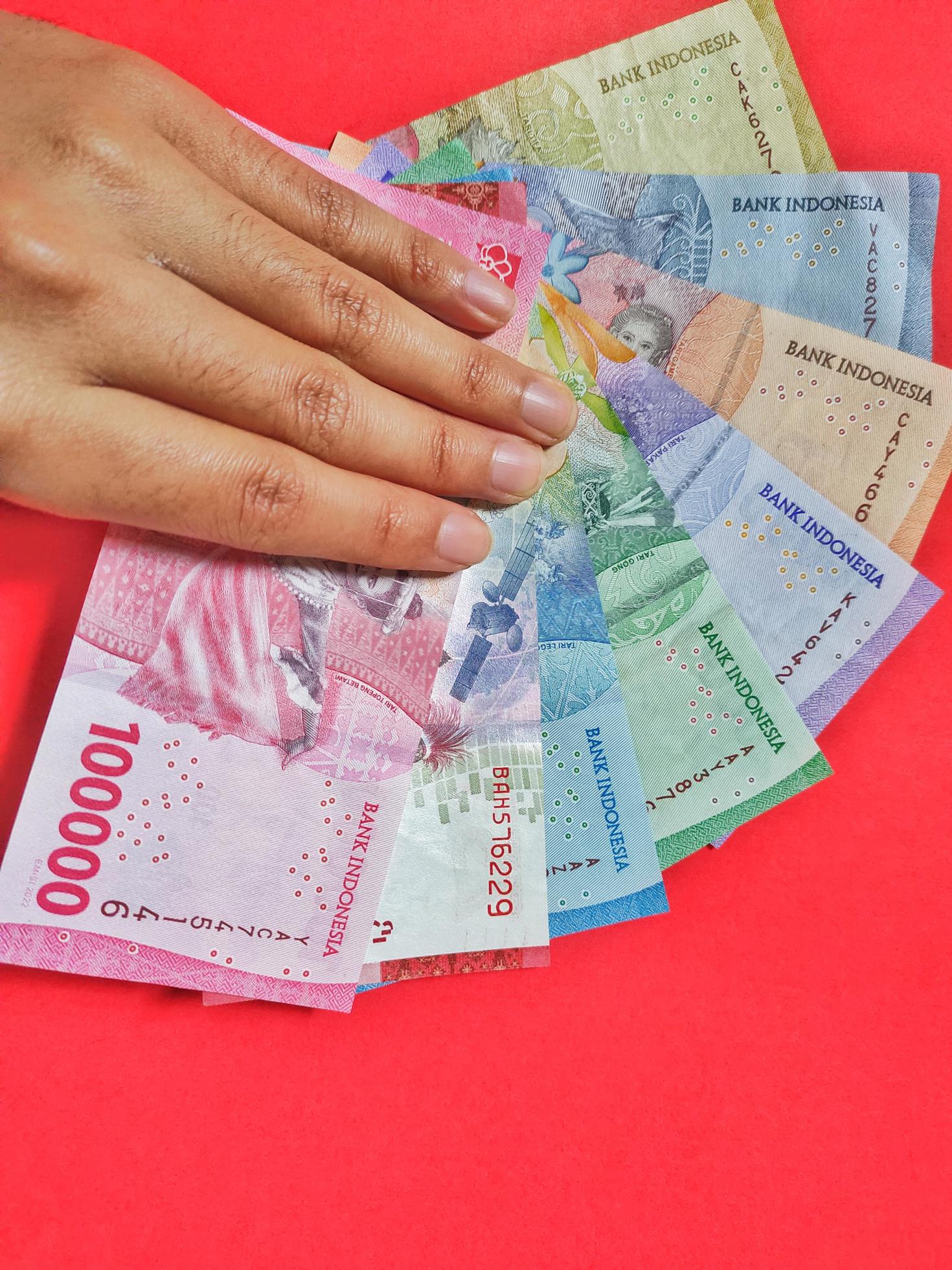 Man Holding New Banknotes Issued In 2022 From Rp 1 000 To Rp 100 000 man-holding-new-banknotes-issued-in-2022-from-rp-1-000-to-rp-100-000