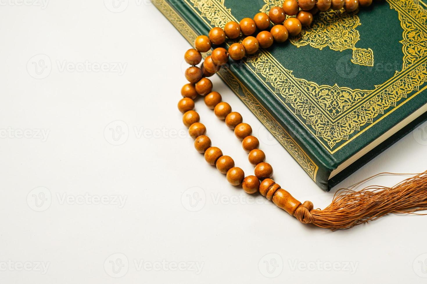 The Holy Al Quran with written arabic calligraphy meaning of Al Quran and rosary beads or tasbih on white background, isolated with copy space. photo