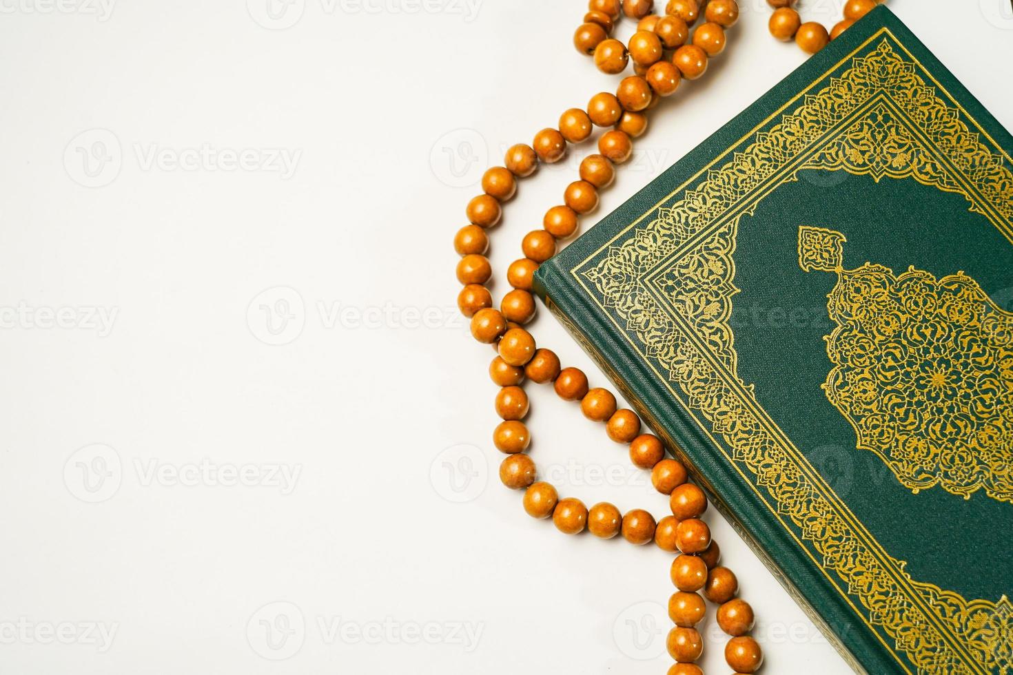 The Holy Al Quran with written arabic calligraphy meaning of Al Quran and rosary beads or tasbih on white background, isolated with copy space. photo