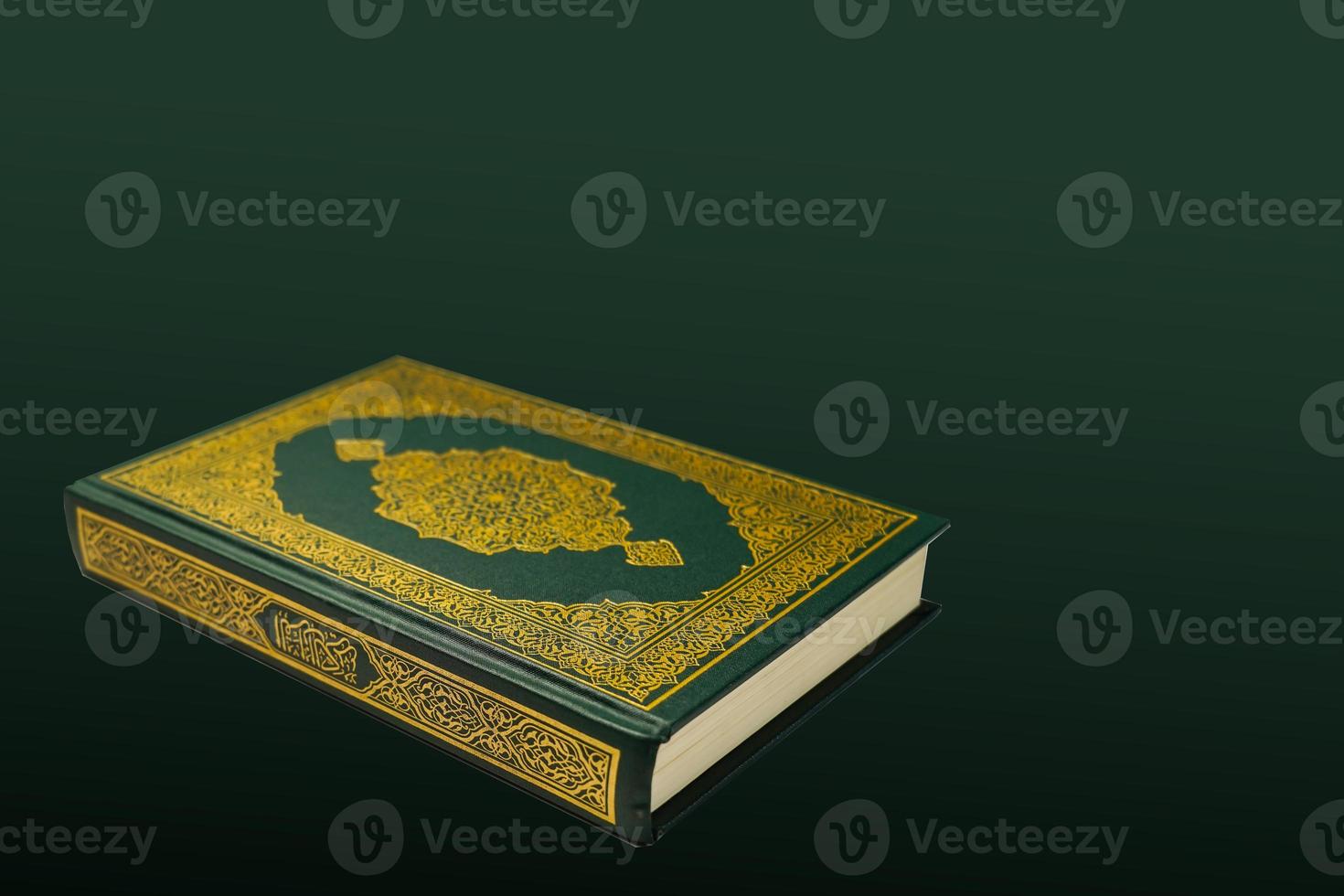 The Holy Al Quran with written arabic calligraphy meaning of Al Quran and rosary beads or tasbih on dark green black background with copy space. photo