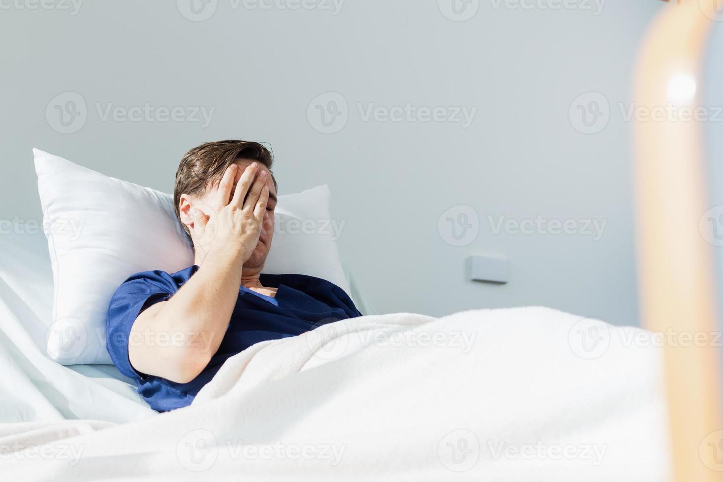 the doctor is examining the patient in the hospital. Caucasian female doctor talking to male patient lying in hospital bed. photo