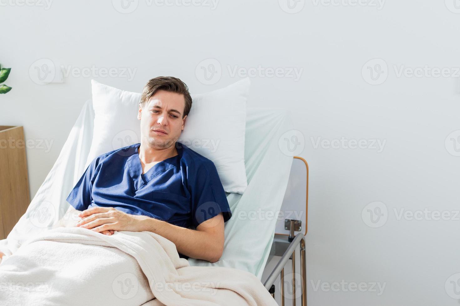 the doctor is examining the patient in the hospital. Caucasian female doctor talking to male patient lying in hospital bed. photo