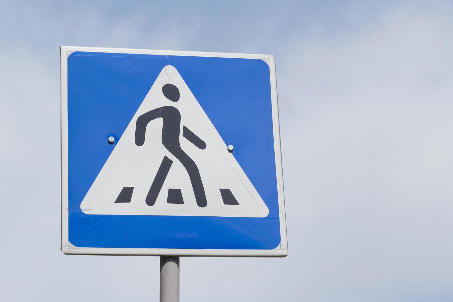 pedestrian crossing road sign against cloudy sky photo
