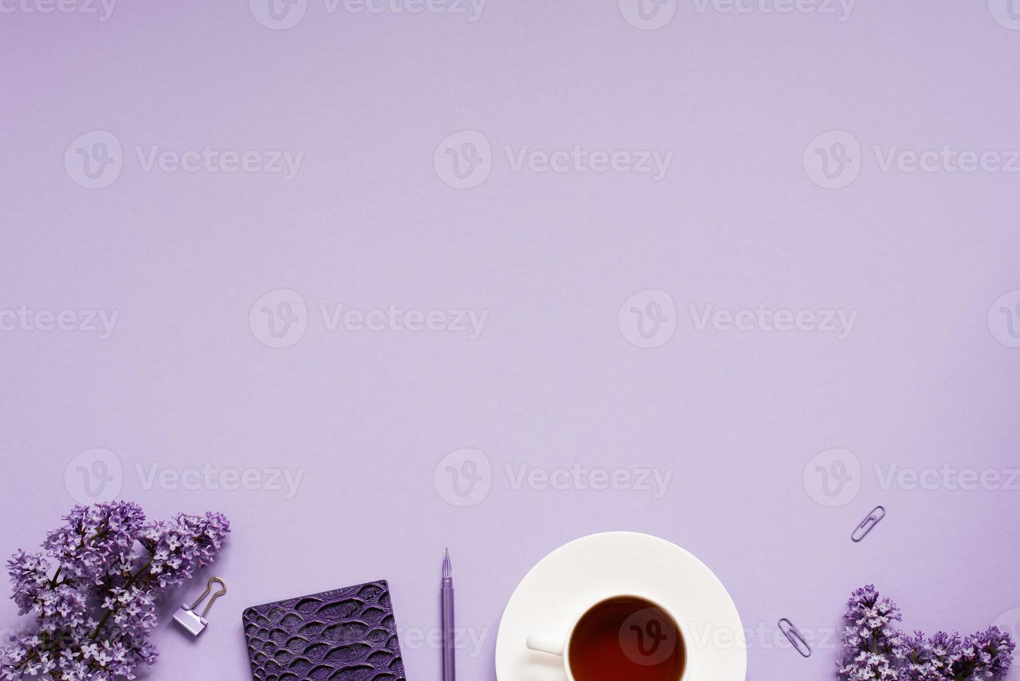 The workspace of a blogger or freelancer Flat lay with a cup of coffee, notebooks and lilac branches, stationery on a lilac background with a copy space photo