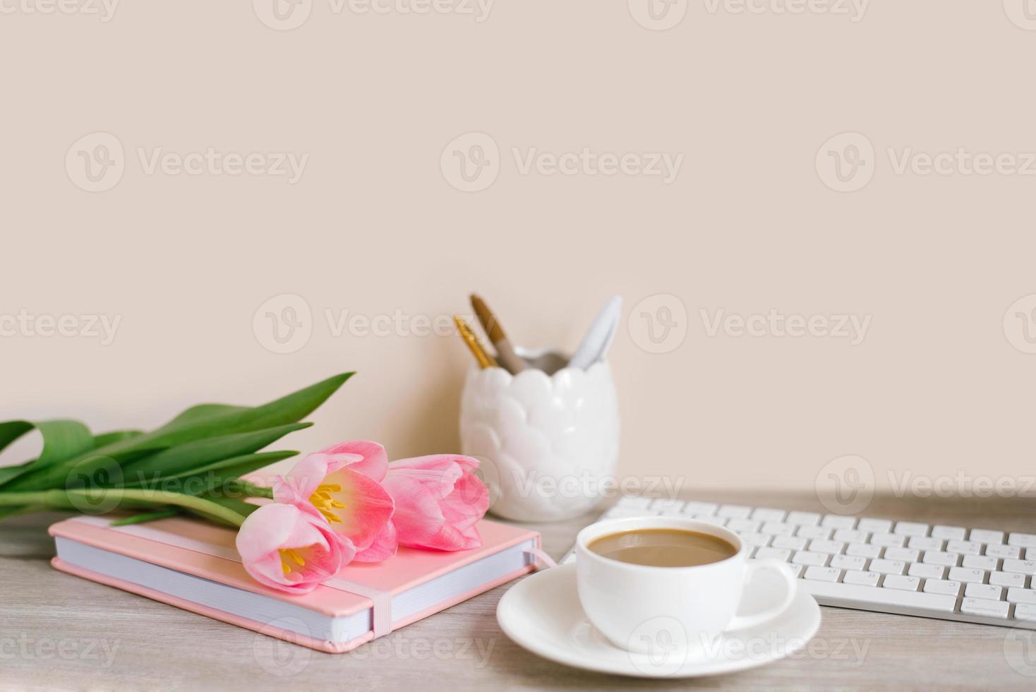 rosado tulipanes con un festivo primavera estado animico y café en un de madera mesa De las mujeres trabajar, hogar oficina y carrera concepto. lado vista. Copiar espacio foto