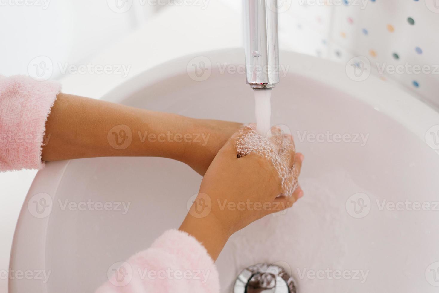 cerca arriba ver de joven niño Lavado manos con jabón en lavabo foto