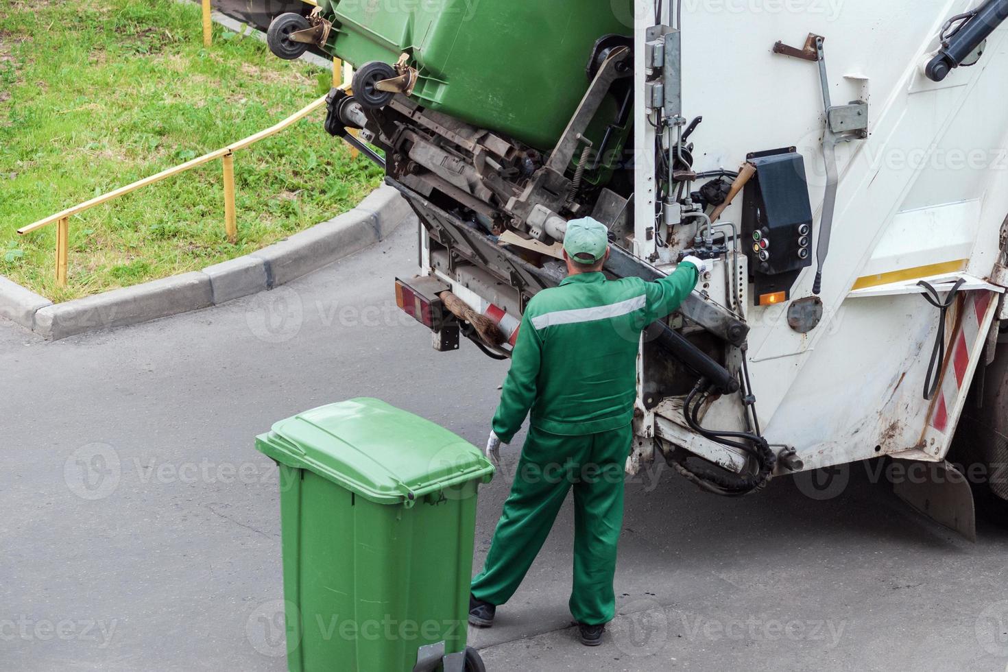 garbage collector loads garbage truck with household waste from garbage cans photo