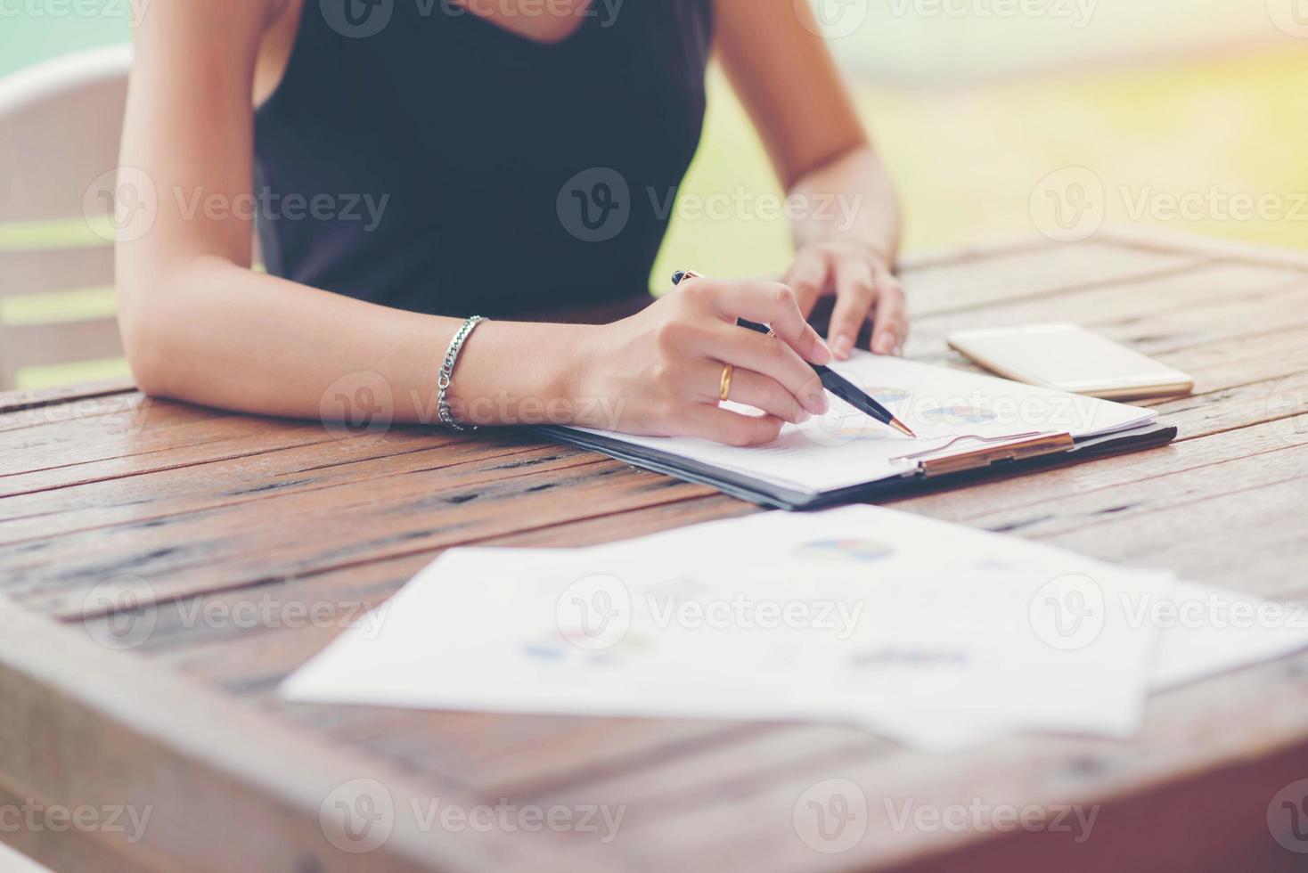 Businessman checking graph with a laptop, phone and alarm clock on the table when the morning light. photo