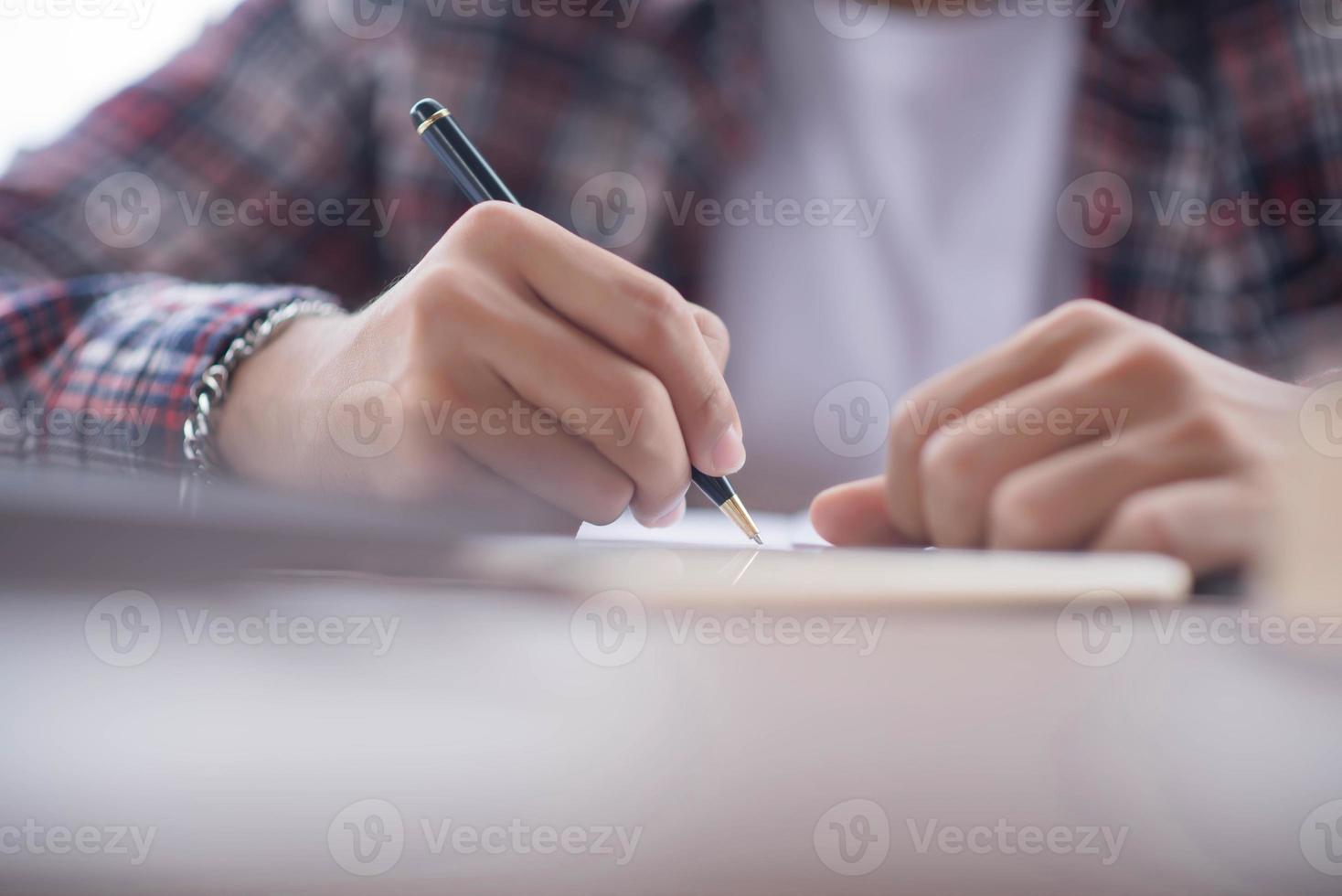 A business man is taking notes into a notebook with an alarm clock on the table. photo