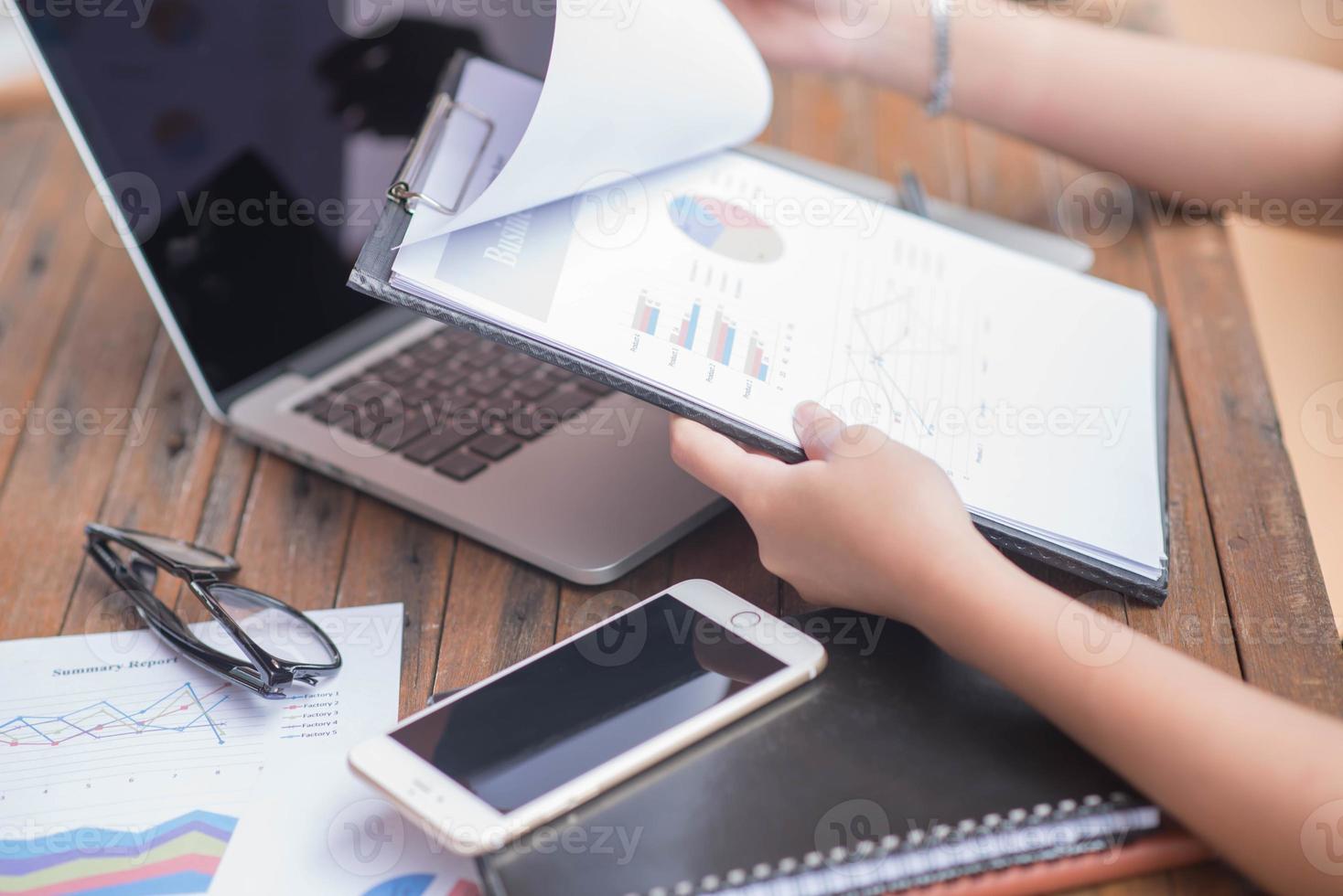 Businessman checking graph with a laptop, phone and alarm clock on the table when the morning light. photo