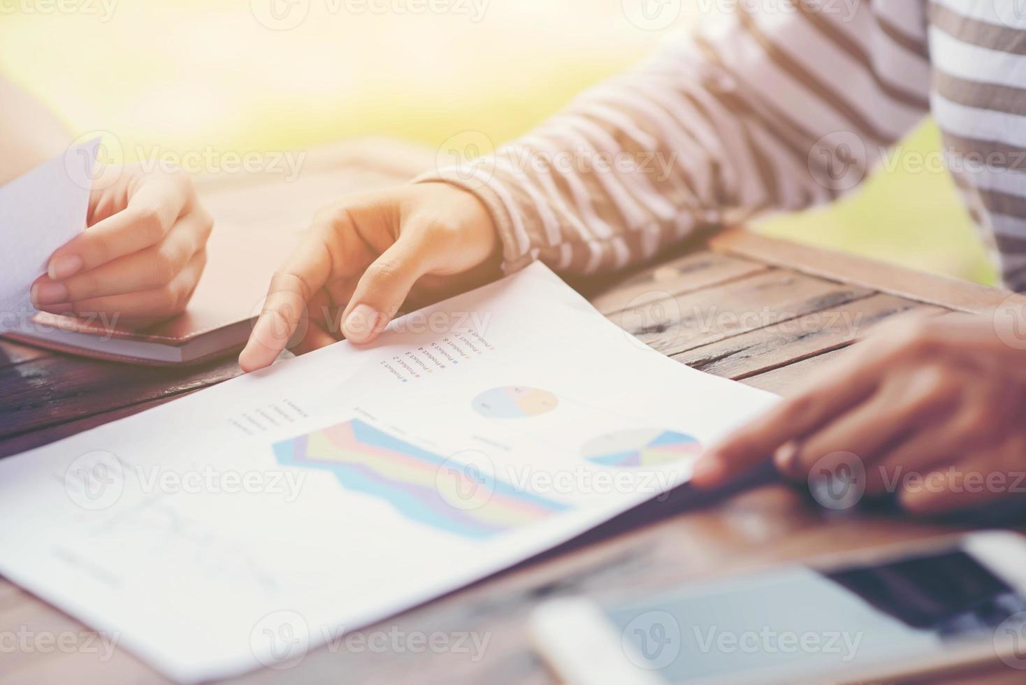 Businessman checking graph with a laptop, phone and alarm clock on the table when the morning light. photo