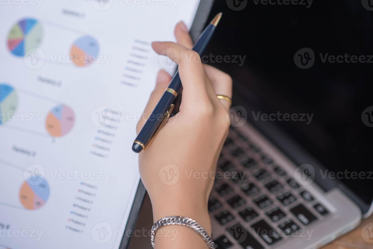 Businessman checking graph with a laptop, phone and alarm clock on the table when the morning light. photo
