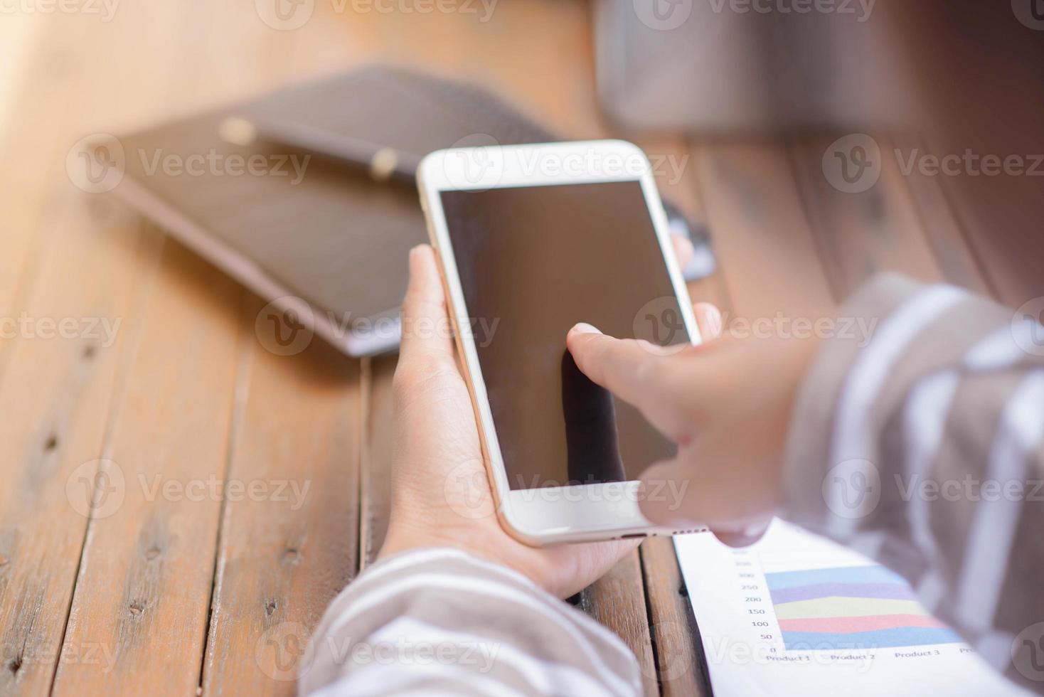 Young businesswoman hard at work at her desk writing notes on a pad from her laptop computer with analytical charts and graphs in front of her, high angle view photo