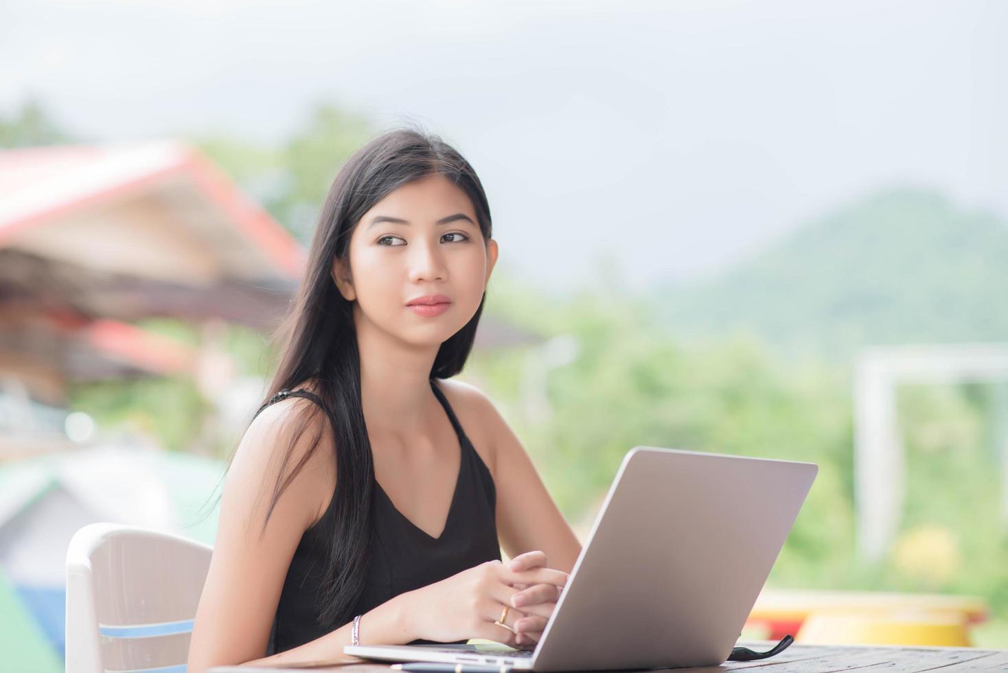 joven mujer vistiendo reloj inteligente utilizando ordenador portátil computadora. hembra trabajando en ordenador portátil foto