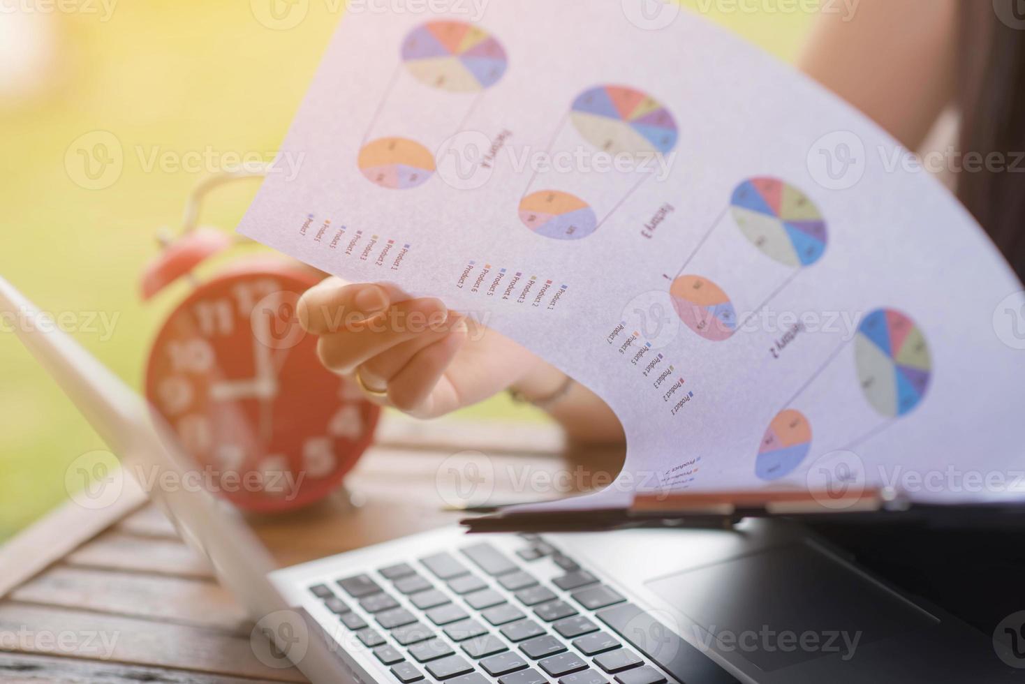 Businessman checking graph with a laptop, phone and alarm clock on the table when the morning light. photo
