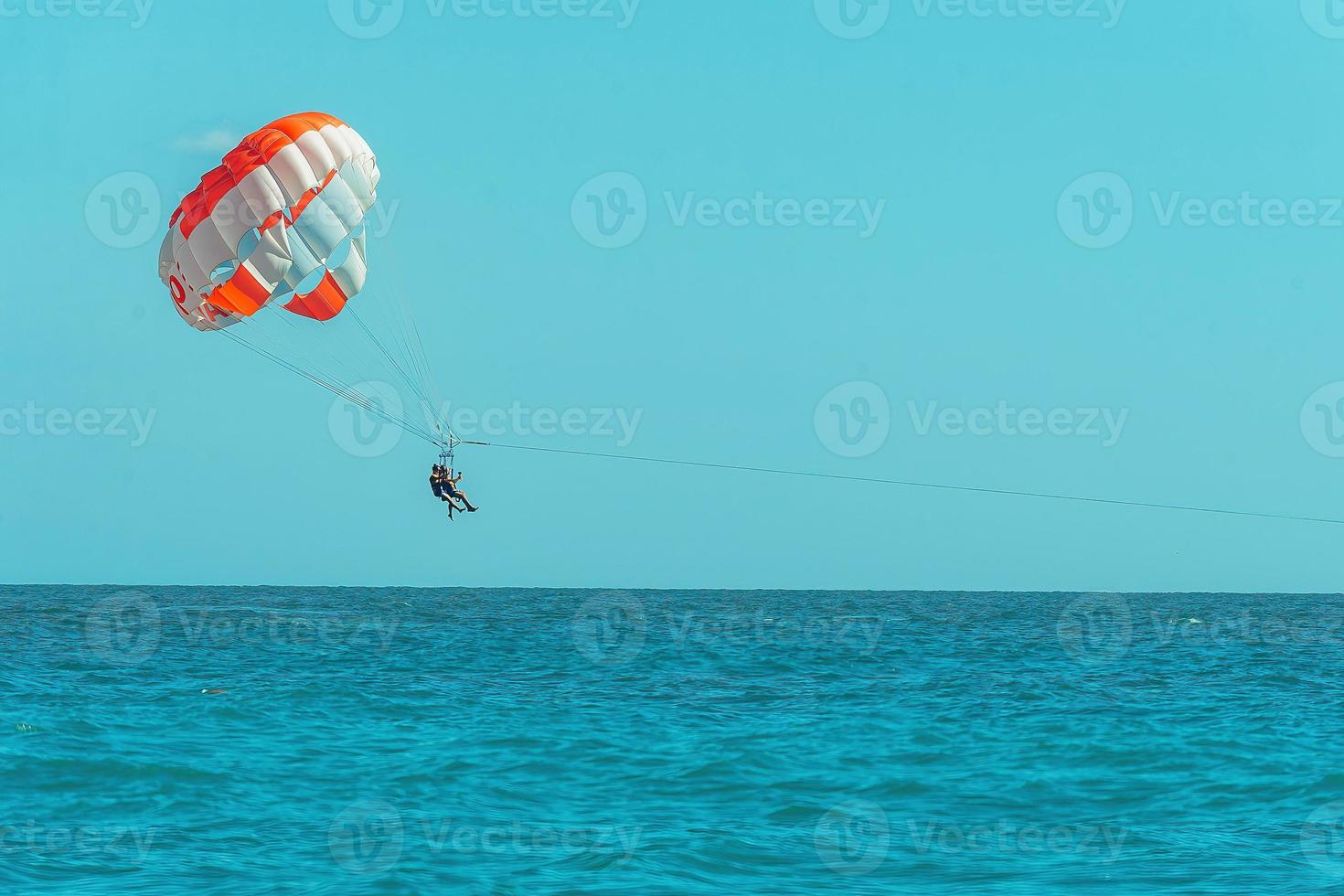 people spend active leisure during holidays at sea, paragliding over water photo