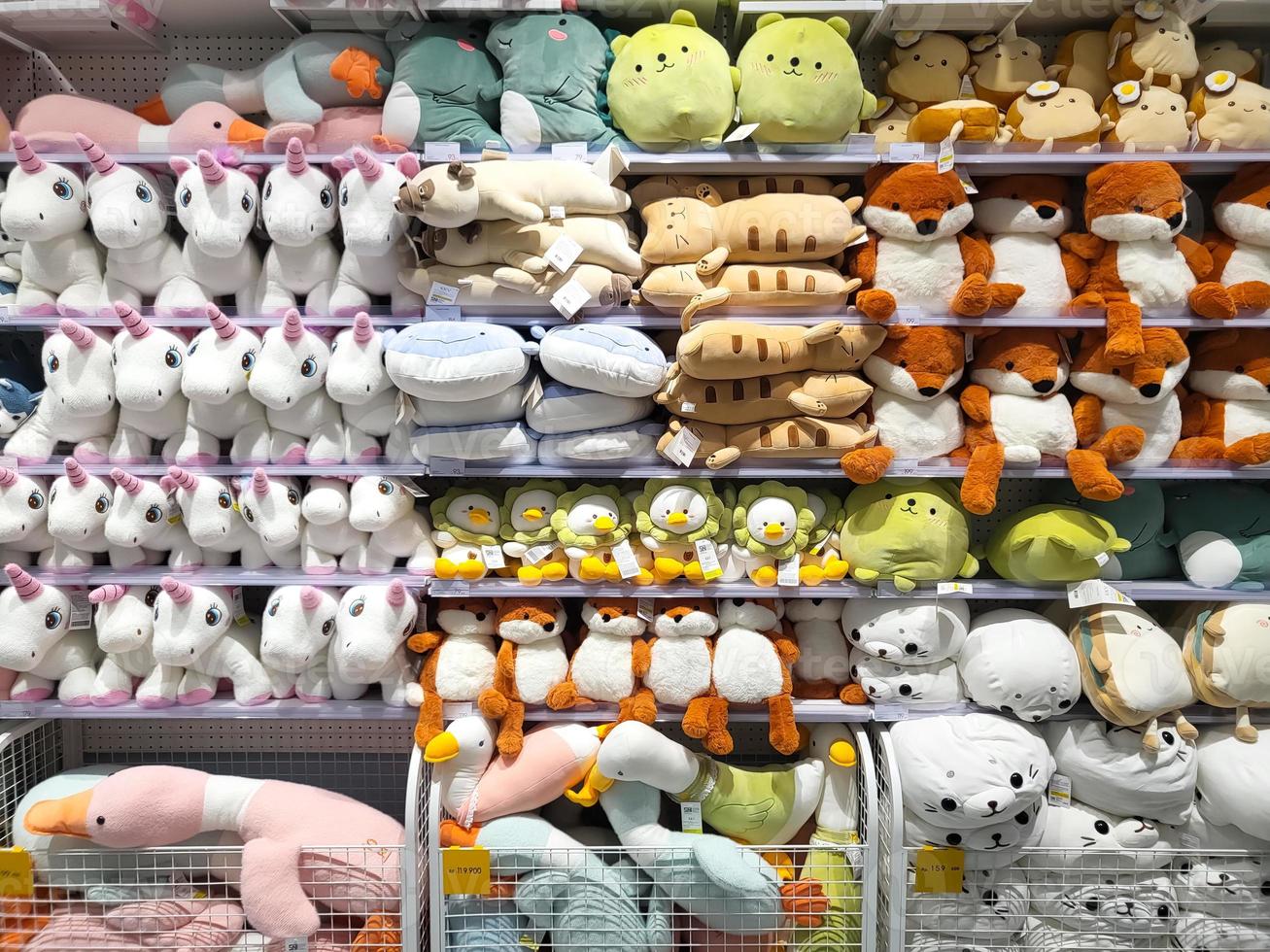 Various kinds of cute animal character dolls are on the sale rack in a shop photo