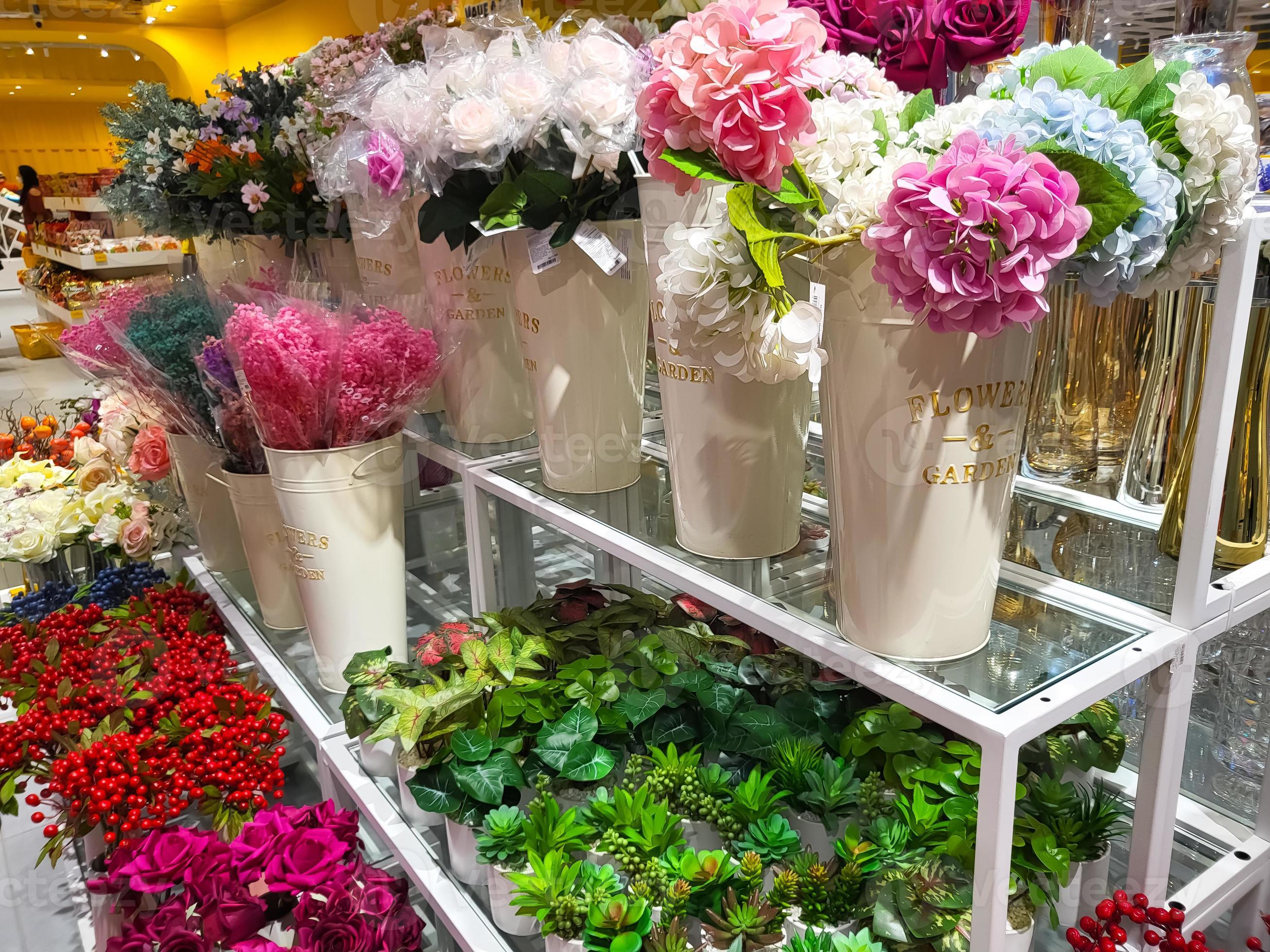 Various types of ornamental plants are on the sale rack in a shop in
