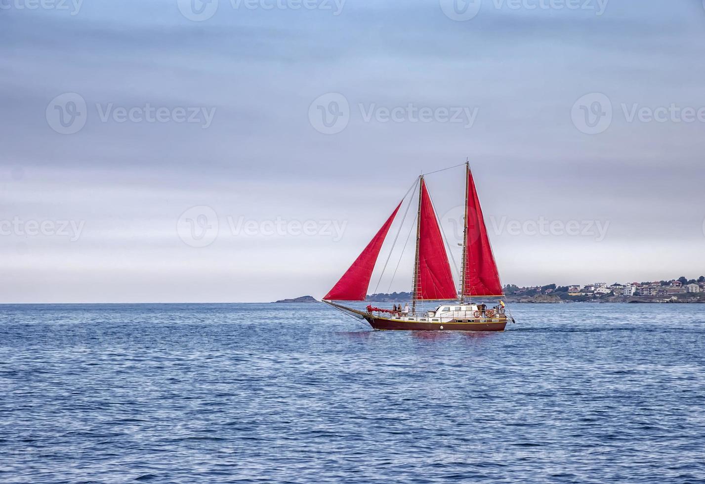 Beautiful composition and mood of a sailing sailboat with red sails photo