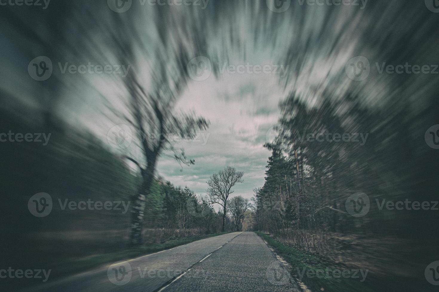 old narrow asphalt road with trees on the side of the road during a car ride in early spring photo