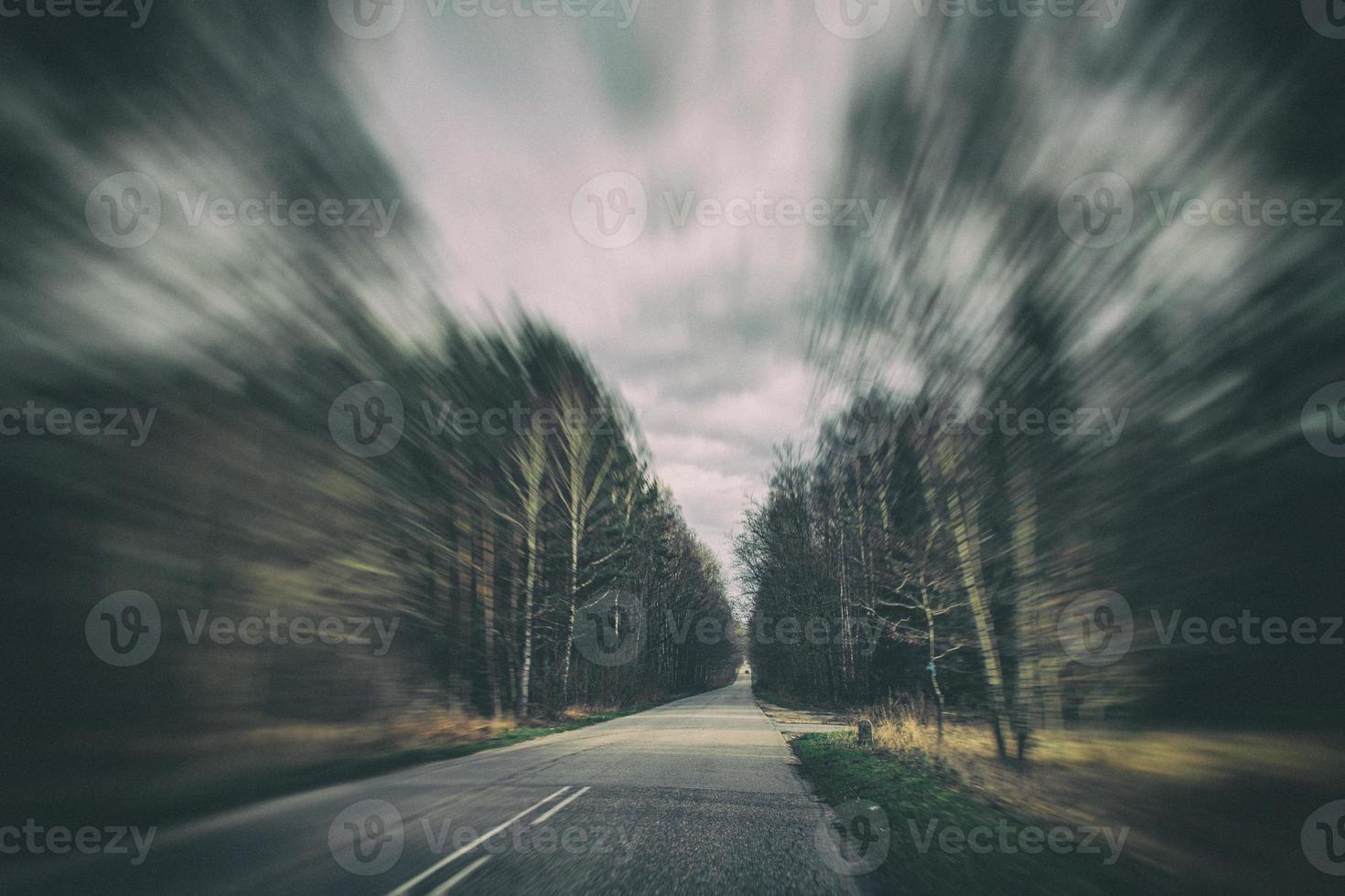 old narrow asphalt road with trees on the side of the road during a car ride in early spring photo