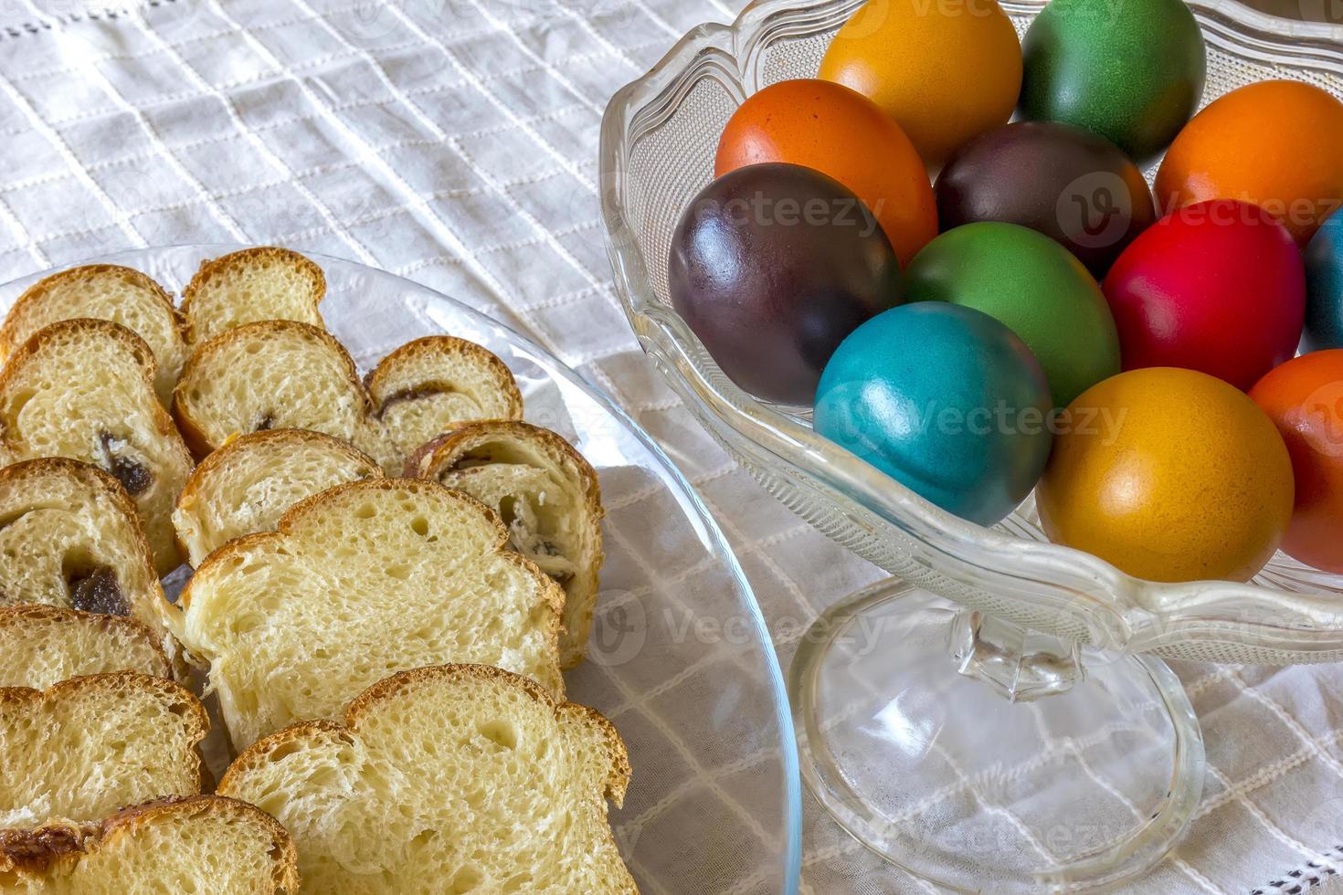 Easter traditional bread and colorful Easter eggs in a plate on the table photo