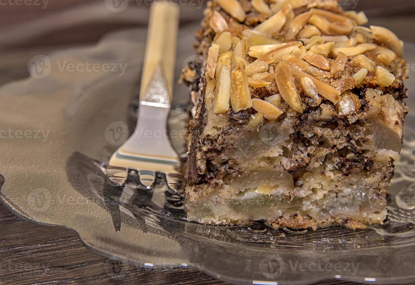 Close view of a delicate piece of chocolate cake, torte with nuts on a plate with a fork. photo