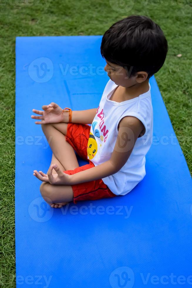 Asian smart kid doing yoga pose in the society park outdoor, Children's yoga pose. The little boy doing Yoga exercise. photo