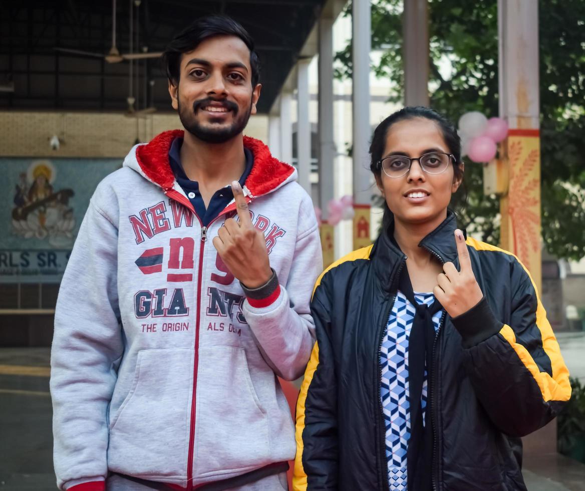 New Delhi, India - December 04 2022 - Unidentified people showing their ink-marked fingers after casting votes in front of polling booth of east Delhi area for MCD local body Elections 2022 photo