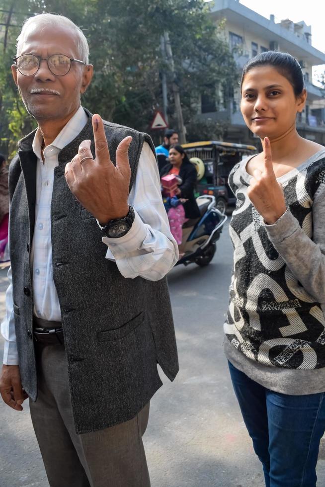 New Delhi, India - December 04 2022 - Unidentified people showing their ink-marked fingers after casting votes in front of polling booth of east Delhi area for MCD local body Elections 2022 photo