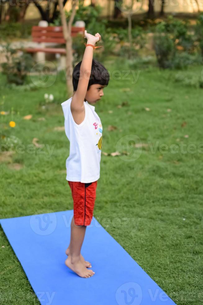 Asian smart kid doing yoga pose in the society park outdoor, Children's yoga pose. The little boy doing Yoga exercise. photo