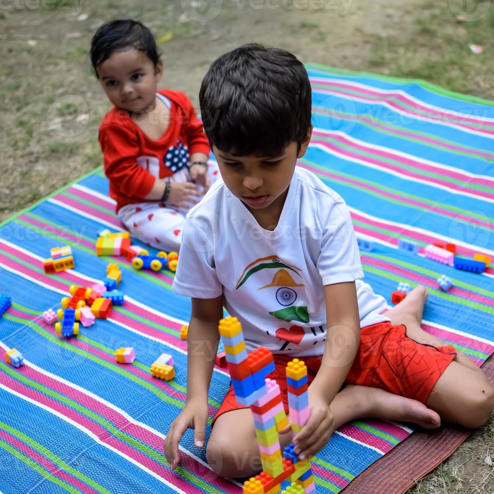 Two happy boys in society park, happy Asian brothers who are smiling happily together. Brothers play outdoors in summer, best friends. Toddler baby boy playing with his happy brother in the garden photo