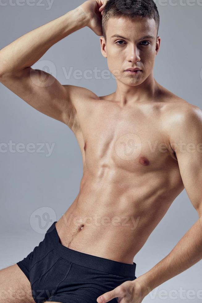 deportivo hombre con bombeado cuerpo en negro pantalones cortos rutina de ejercicio posando aptitud foto