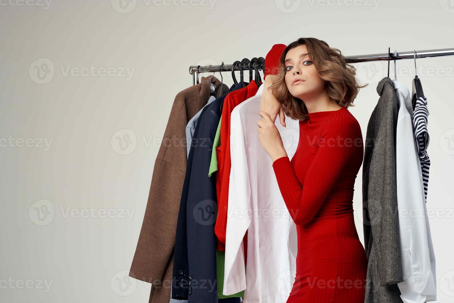 hermosa mujer en un rojo chaqueta cerca el guardarropa ligero antecedentes foto