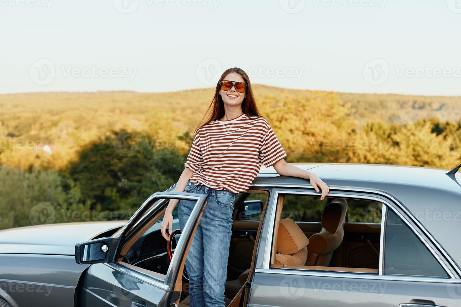 A young woman driver looks out of the car at the autumn landscape and smiles satisfactorily photo