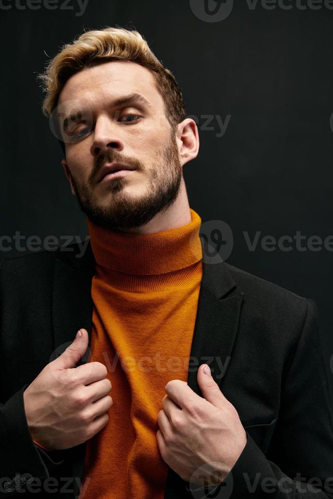 man in orange sweater and black coat gesturing with hands cropped view blond model photo