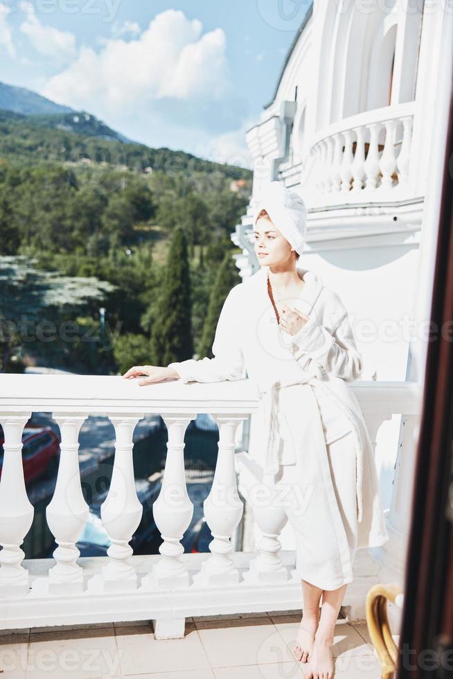 Portrait woman in a white robe on the balcony bit on green nature Perfect sunny morning photo