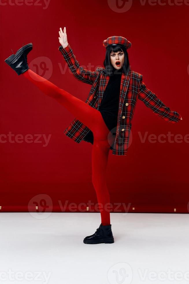 emotional woman with her leg raised bright clothes red background photo