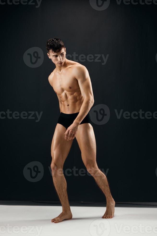 man in black panties with naked muscular body dark background photo