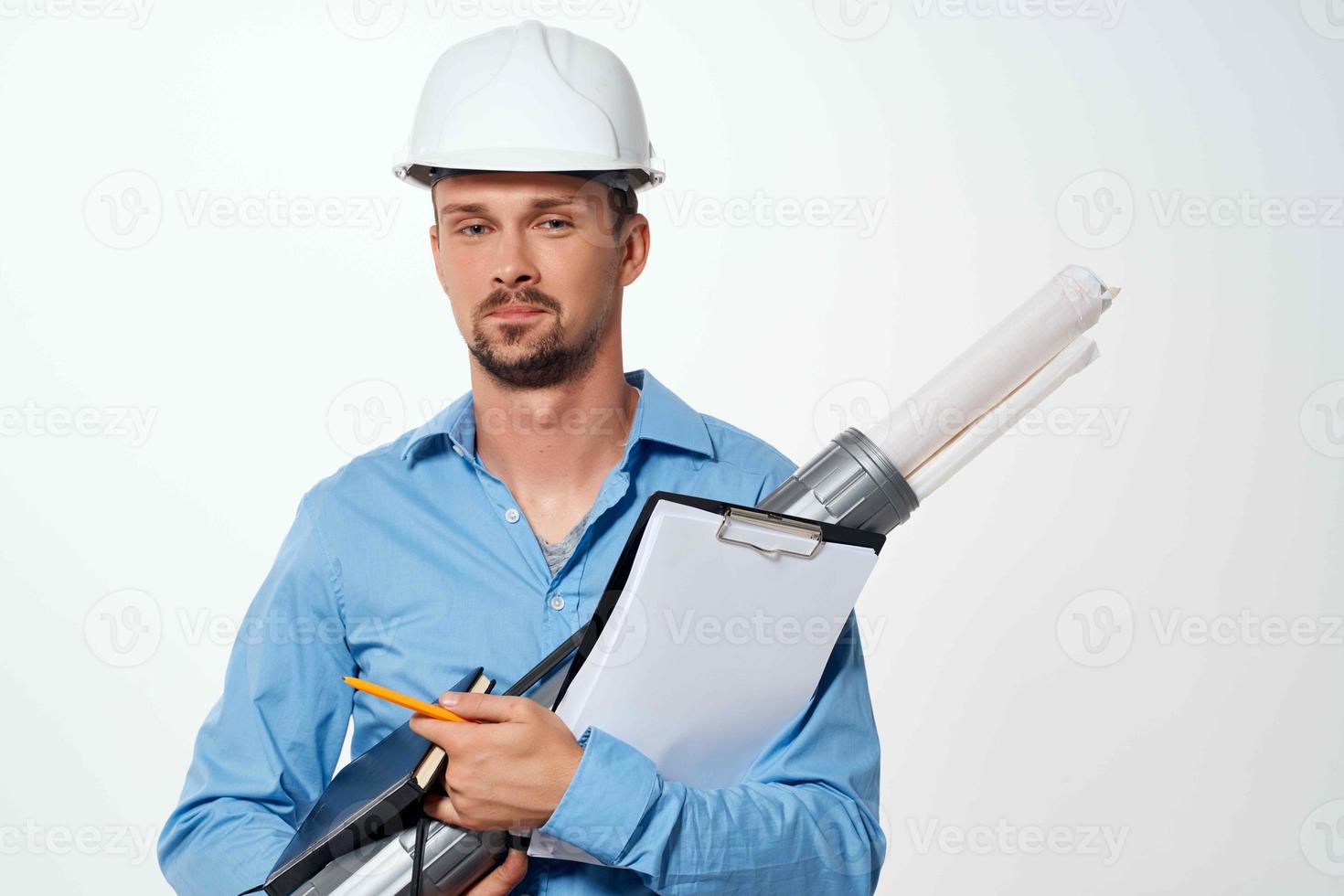 un hombre en un azul camisa en un construcción casco planos para construcción profesionales foto