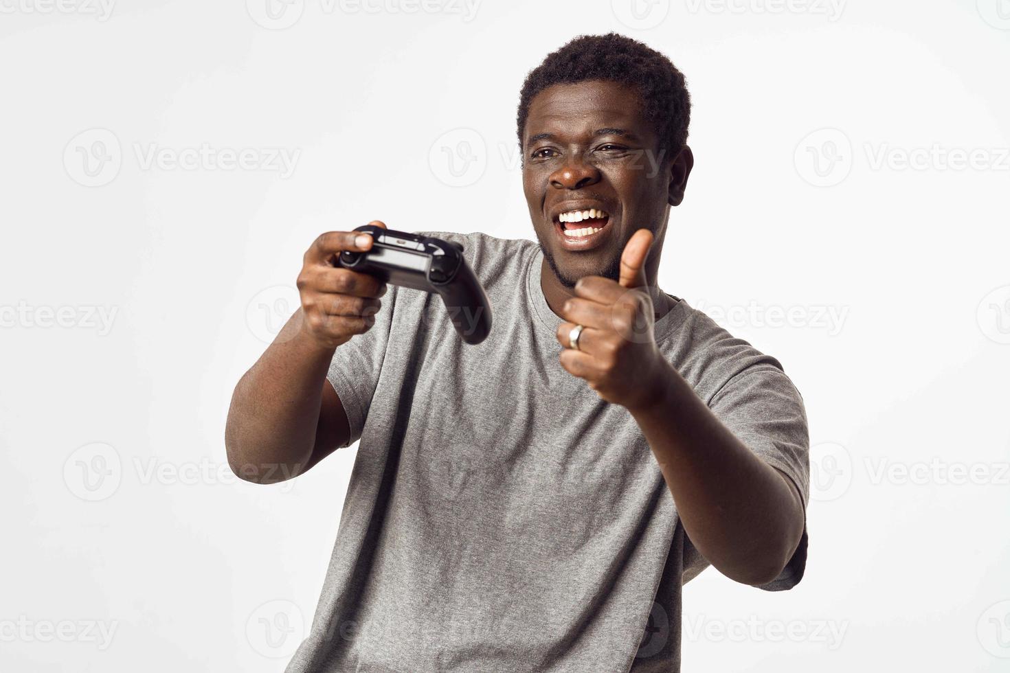 Cheerful man of African appearance with a joystick in his hands plays video games photo