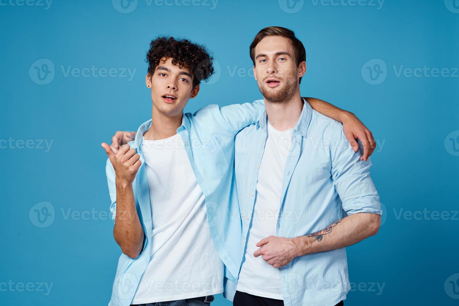 man with tattoo hugs his friend on blue background and cropped view fun photo