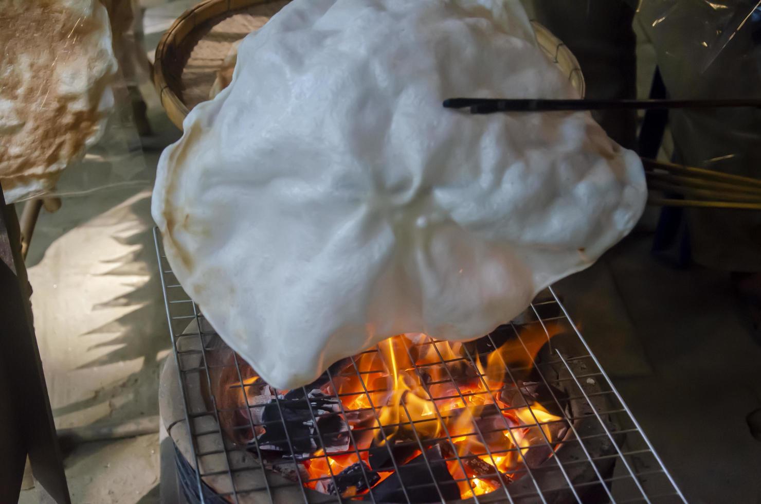 How to cook kite crackers or khao kriap wow by grilling dough sheets on charcoal stove, an ancient Thai dessert. photo