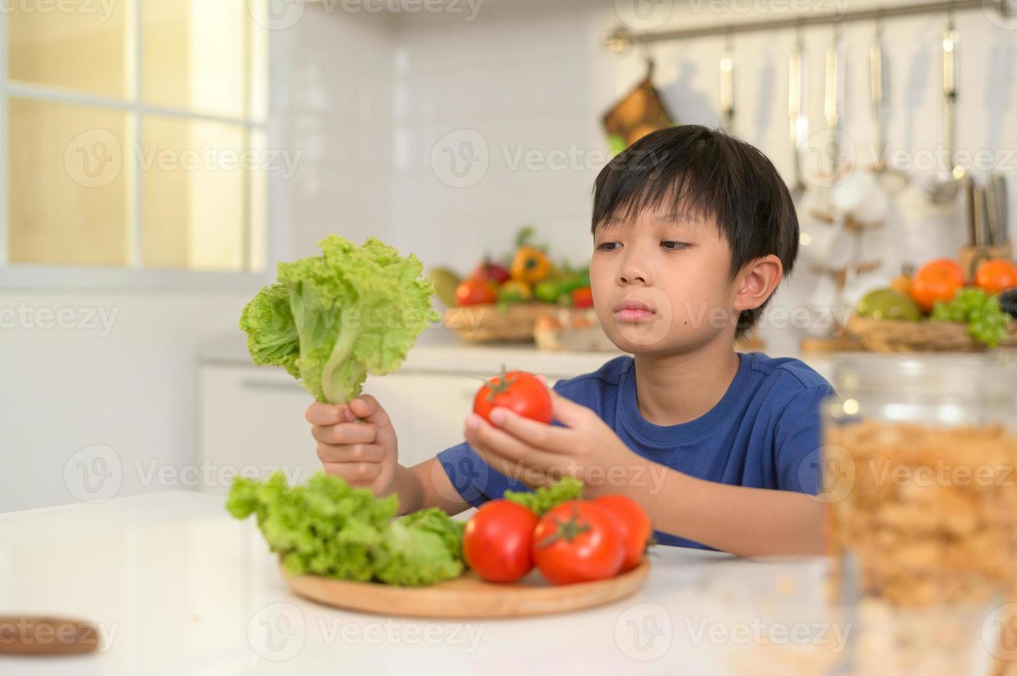 Asian boy feeling bored , unhappy to eat vegetables , health care concept photo