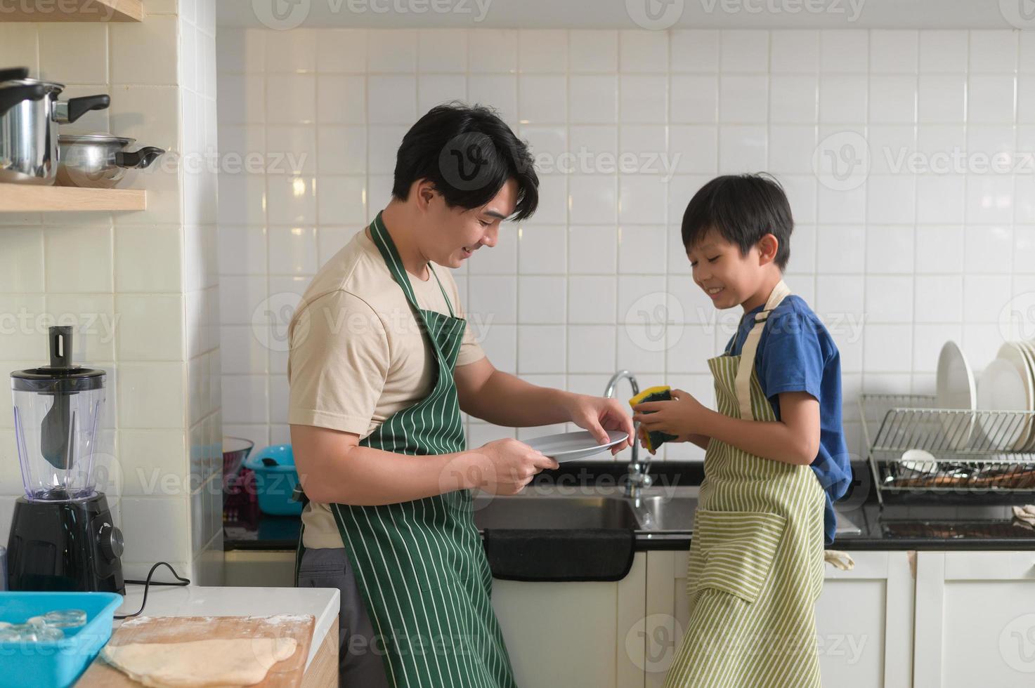 Happy smiling Young Asian father and son washing dishes in kitchen at home photo