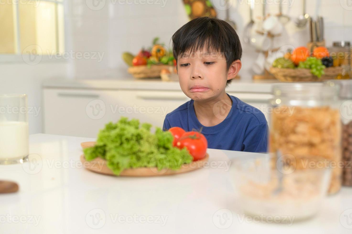 asiático chico sensación aburrido , infeliz a comer vegetales , salud cuidado concepto foto