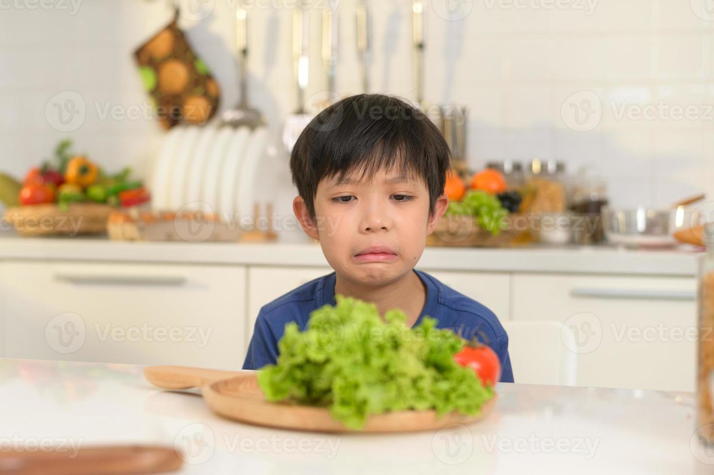 asiático chico sensación aburrido , infeliz a comer vegetales , salud cuidado concepto foto