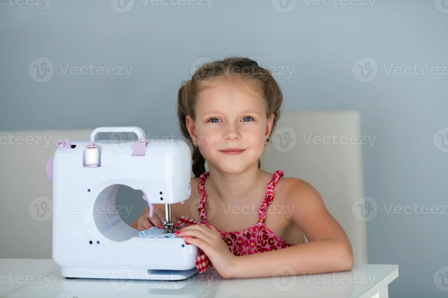 un hermoso, sonriente joven niña de coser en un un moderno de coser máquina. pasatiempo. foto